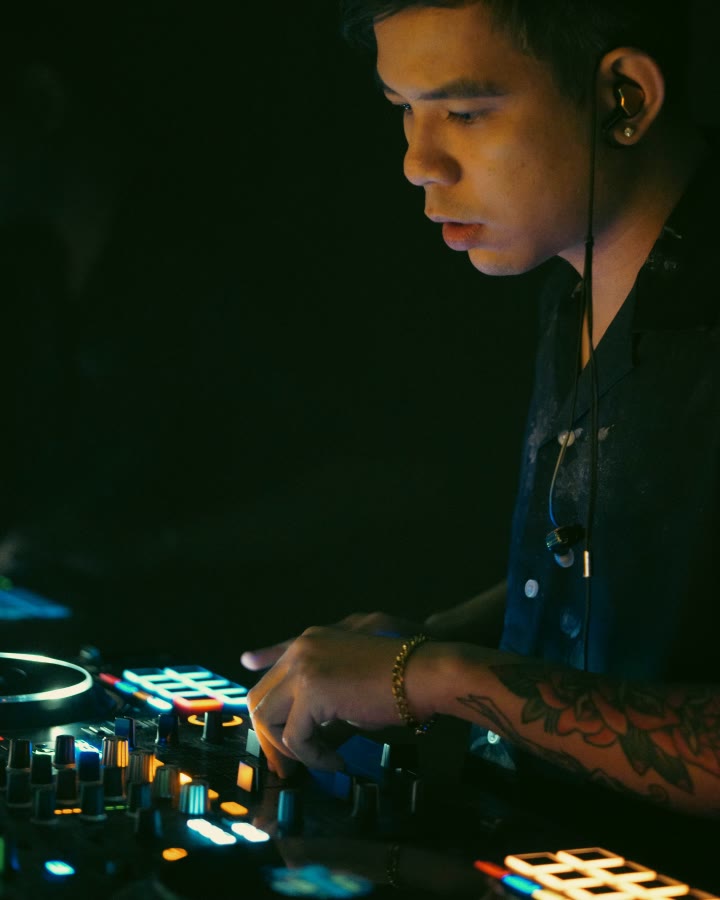 REIDEL in profile at the controller, in-ear monitor in, under warm light.